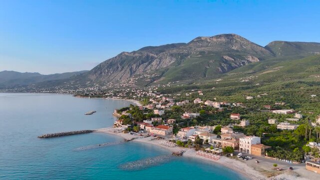 Aerial view of Mikri Mantineia coastal village near Kalamata, Greece, with calm blue sea, pebble beach, breakwater, seaside houses and mountain landscape in the Peloponnese
