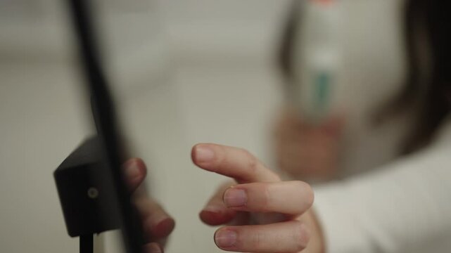 Closeup of esthetician female in beauty salon setting up modern laser machine for facial skincare treatment, hand touching screen to select photorejuvenation program. Shooting in slow motion.