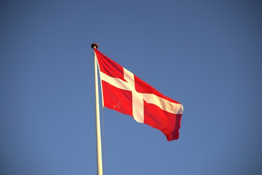Danish flag Dannebrog on flagpole against clear sky