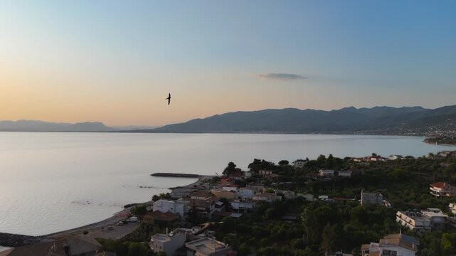 Seagulls Flying Over Coastal Village and Calm Sea at Sunset in Mikri Mantineia near Kalamata, Greece, Aerial Drone View of Mountains and Bay