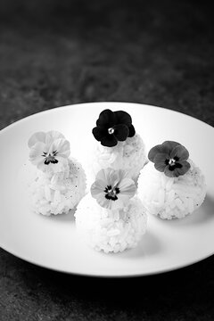 Monochrome edible flower temari rice balls on a white plate