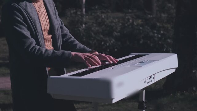 Atmospheric cinematic scene of musician playing white digital piano outdoors in soft evening light. Artistic instrumental performance surrounded by peaceful nature