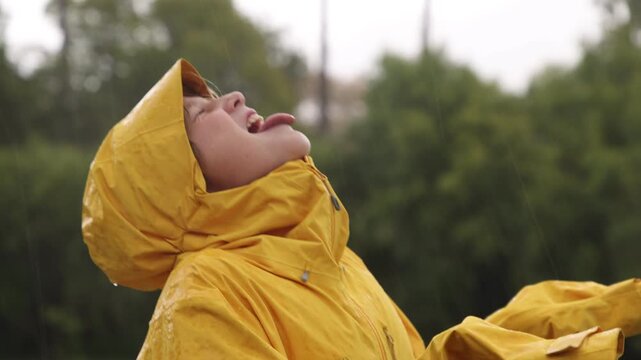 young boy wearing yellow raincoat enjoying the rain