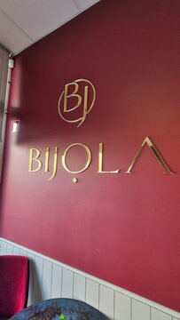 Vilnius Lithuania 18.04.2026 Bijola confectionery and dessert boutique logo on elegant red interior wall with golden letters bakery and pastry shop concept