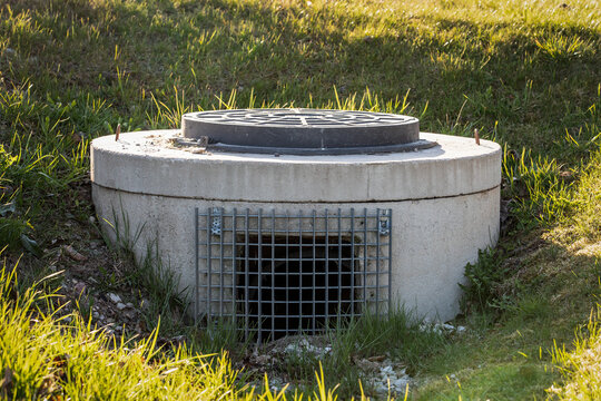 Concrete Stormwater Drainage Manhole With Protective Metal Grate in Grass