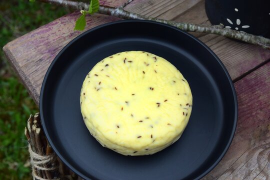 Traditional Latvian Midsummer caraway cheese on a black tray and wooden stool from a high angle