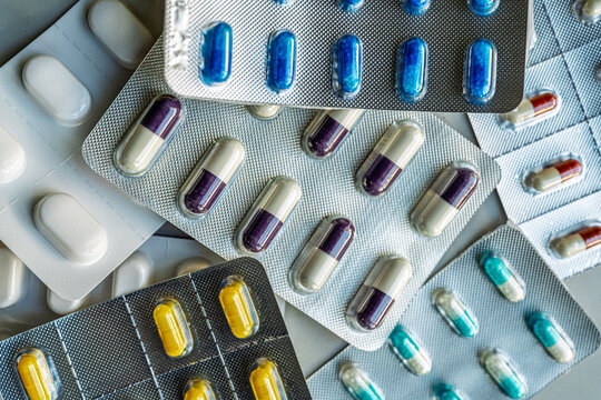 Overhead view of mixed medication blister packs and colorful capsules