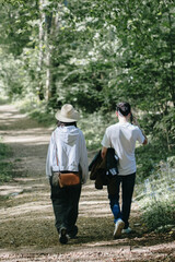 Fototapeta premium A vertical portrait of a young couple from the back walking together along a forest path.