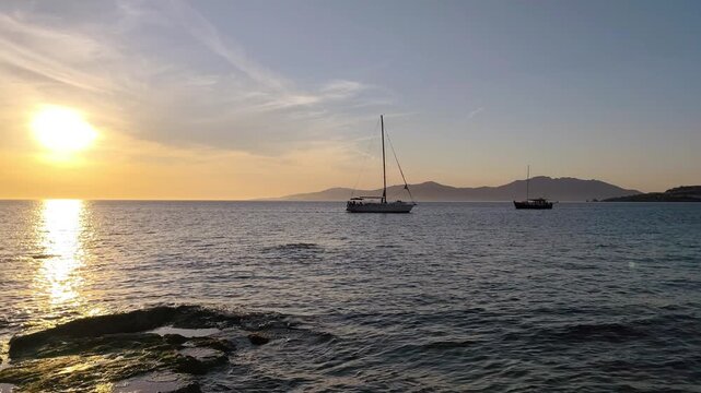 View of a breathtaking golden sunset over the Aegean Sea, seen from the Old Harbor of Mykonos island, Greece.