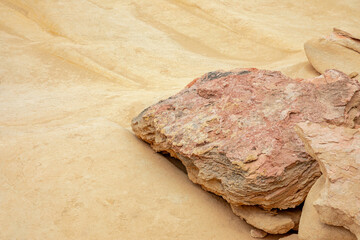 Large reddish rock rests on a smooth sandy canyon slope, creating a striking contrast of textures. Ideal minimalist background for travel and desert nature themes. © Svitlana
