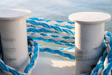 Naklejka premium Blue and white mooring ropes tied to harbor bollards.