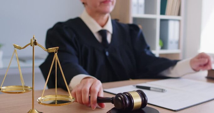 Female judge authority writing, using gavel, hammer bangs to sentence in court of law, accuse guilty, proclamation, passes judgement, hitting table to get attention, punctuate rulings, final decision