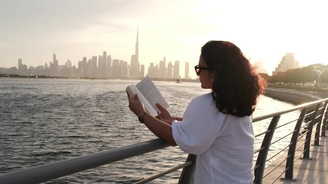 young woman enjoying outdoor reading and reflection with Dubai skyline at golden hour