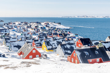 Dense greenlandic capital residential neighborhood with colorful Inuit homes, snow covered rooftops and arctic fjord shoreline, Nuuk, Sermersooq, Greenland © vadim.nefedov