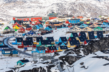 Colorful hillside homes and compact residential district beneath snowy mountains in a winter arctic townscape of Ilulissat, Greenland. © vadim.nefedov