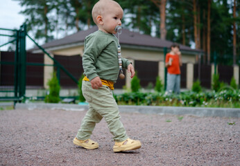 Fototapeta premium Carefree toddler boy playing outdoors on warm sunny summer day. Joyful little adventurer exploring nature path in park with innocent happiness. Child enjoying carefree summer moments in grass