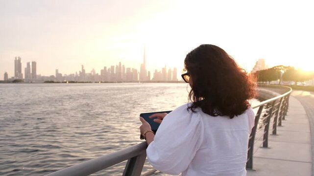 Businesswoman working remotely with laptop with Dubai cityscape background, 4k Dubai lifestyle video
