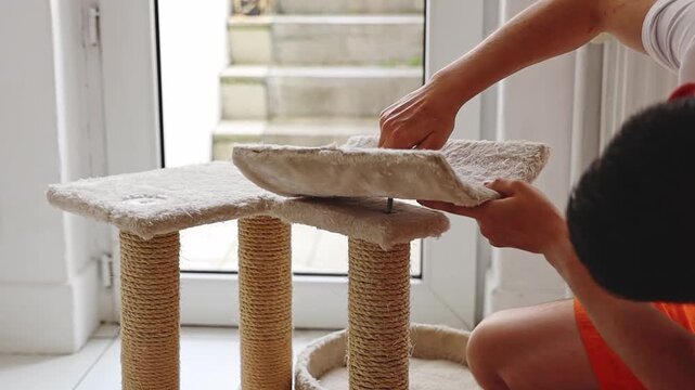 The guy assembles the cat house and tightens the bolts.