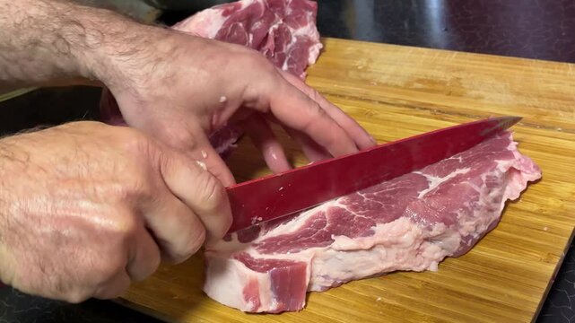 Man cut meat steak, beef pork neck cooking, Cook Butcher. The chef cuts the meat for cooking. Neck carbonate with vegetables cutting on ktchen for bbq grill, marinade. 