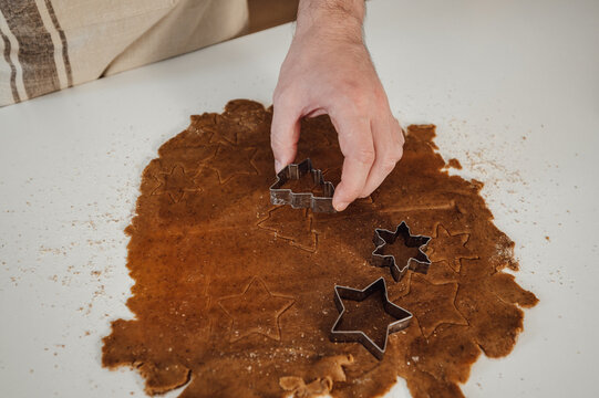 Man cutting out gingerbread cookies from the dough for christmas