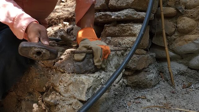 Hammering a small guide rod into a wall with a sledgehammer