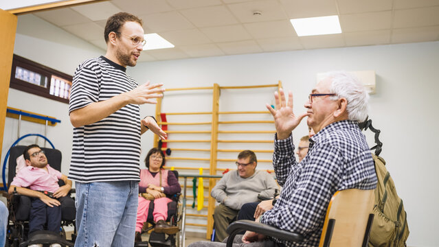 People with diverse abilities participating in an inclusive communication class, a man teaching sign language to adults