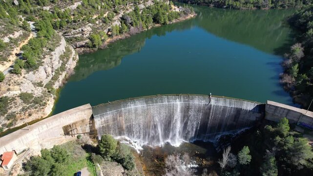 Forward reveal aerial shot of full of water Margalef reservoir on sunny winter day. Tarragona Province, Spain.