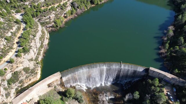 Tilt down aerial shot of Margalef dam and reservoir on sunny winter day. Tarragona Province, Spain.