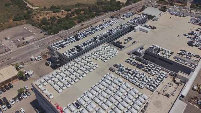 Aerial view of a large car dealership in Israel with hundreds of vehicles stored on the rooftop and surrounding lots
