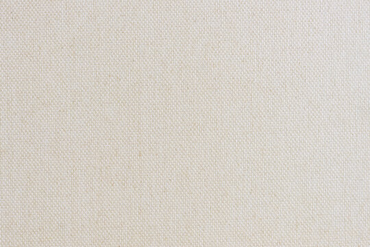 High-resolution macro of light ivory canvas fabric with visible weave pattern. Clean organic textile background