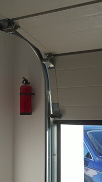 Sectional garage door closes inside a residential garage with a red fire extinguisher on wall