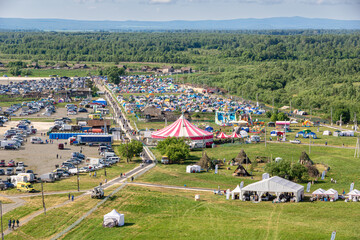 Aerial view of festival entertainment and camping zones with parking and emergency vehicles in rural landscape © Dmitrii