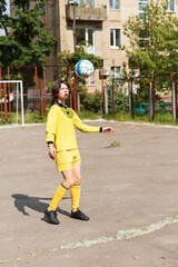 Fototapeta premium Teenage boy soccer player watching ball in air during outdoor training on residential playground
