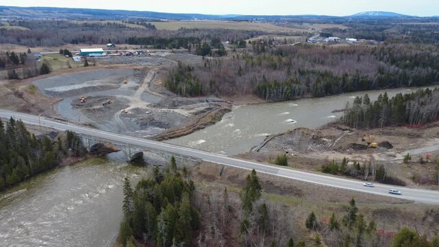 Drone aerial video of a new bridge foundation construction site beside the old Arthur-Bergeron bridge over the flood-swollen Mitis Salmon River in Gaspesie, Quebec, Canada.