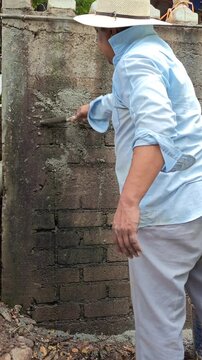 Mason applying a thin layer of cement to a brick cistern wall
