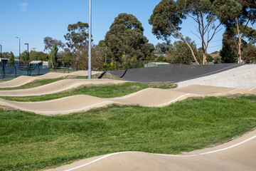 Fototapeta premium A modern BMX pump track and bicycle skills course at a suburban sports facility in Sunbury Melbourne, Australia, featuring smooth and compacted sand berms, rollers and undulating track surfaces