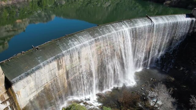 Tilt down aerial shot of Margalef dam with water flowing through on sunny February day. Tarragona Province, Spain.