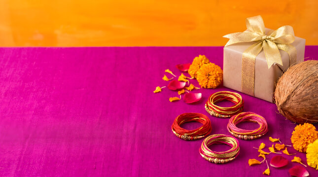 Red gold bangles beside wrapped gift box coconut and marigold on purple fabric surface