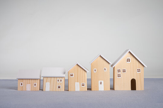 Row of wooden house models of increasing size . Real estate investment success, property market trends, and rising home values.
