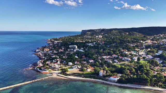 Azure bay waterfront aerial view, crystal water lapping against rocky cove, treelined streets and white