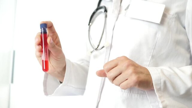 A doctor in a white coat holds a sealed test tube containing a red blood sample, ready for hematological or viral laboratory analysis.