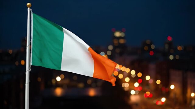 Ireland flag waving on a flagpole at night with blurred city lights in an urban area