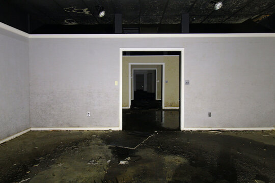 Doorway Leading Through Empty Rooms of Abandoned Building with Wet Damaged Floor