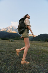 Fototapeta premium A woman hiking outdoors with a backpack in a mountainous landscape, wearing shorts and boots. A lifestyle moment of adventure, exploration, and outdoor fitness in nature.