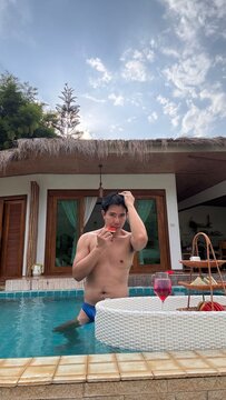 Handsome male model relaxing happily by the outdoor swimming pool in summer.