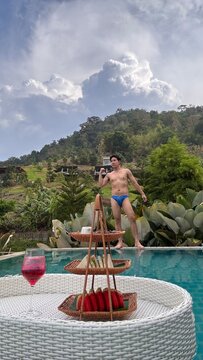 Handsome male model relaxing happily by the outdoor swimming pool in summer.