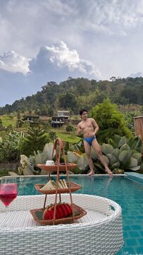 Handsome male model relaxing happily by the outdoor swimming pool in summer.
