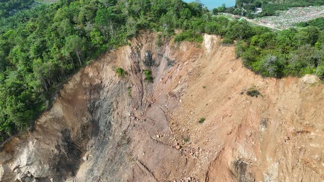 Aerial view of a large landslide or mudslide in a forested area with a body of water.