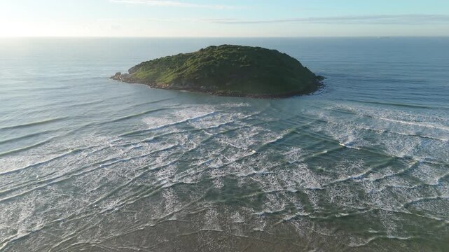 Aerial view of the island in the sea with waves interfere next to it