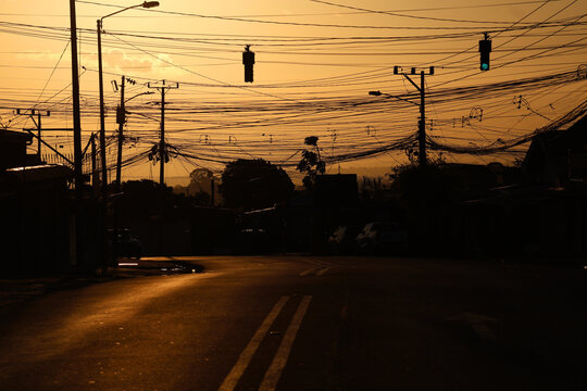 Urban street view with chaotic electrical cables and traffic light at dusk